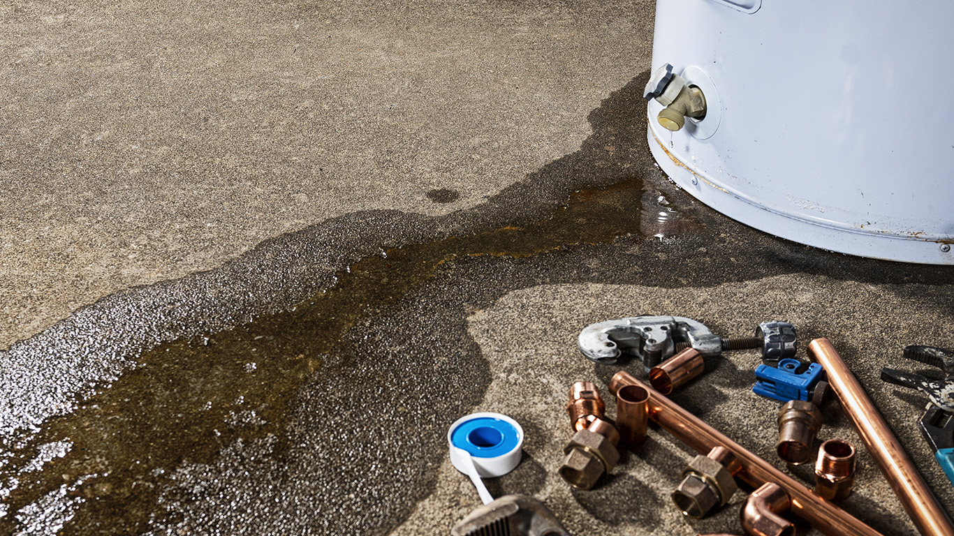 A leaking faucet on a domestic water heater with tools and fittings to replace appliance